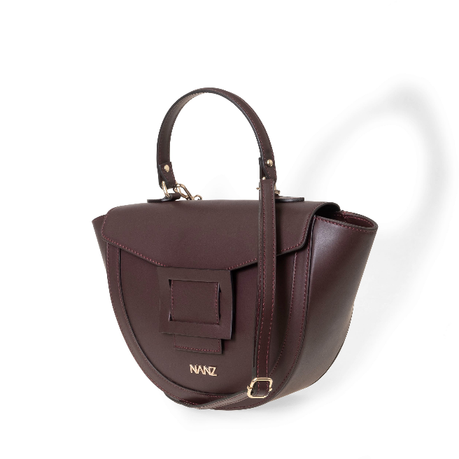 A burgundy, leather NANZ handbag with a structured, trunk-inspired design, featuring a top handle and a detachable crossbody strap.